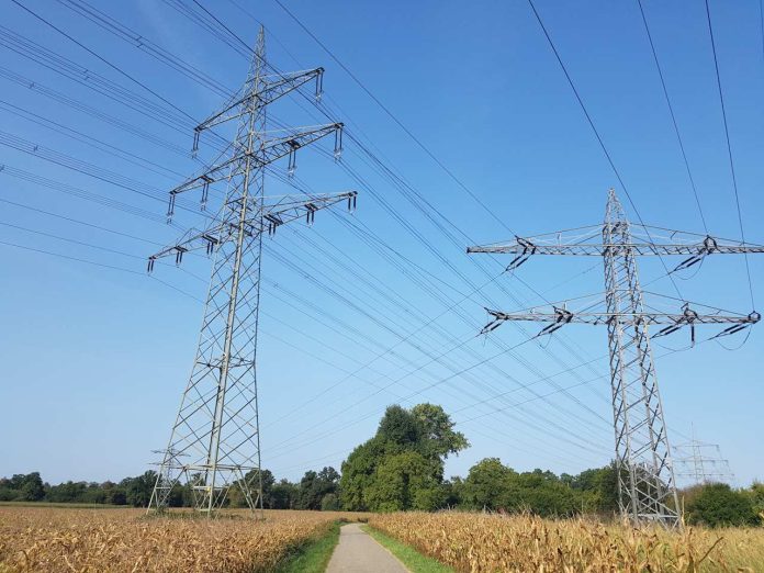 Zwei Strommasten im Feld: Die Sektorkopplung spielt in Szenarien zur Zukunft des Energiesystems eine tragende Rolle. Koalitionsverhandlungen